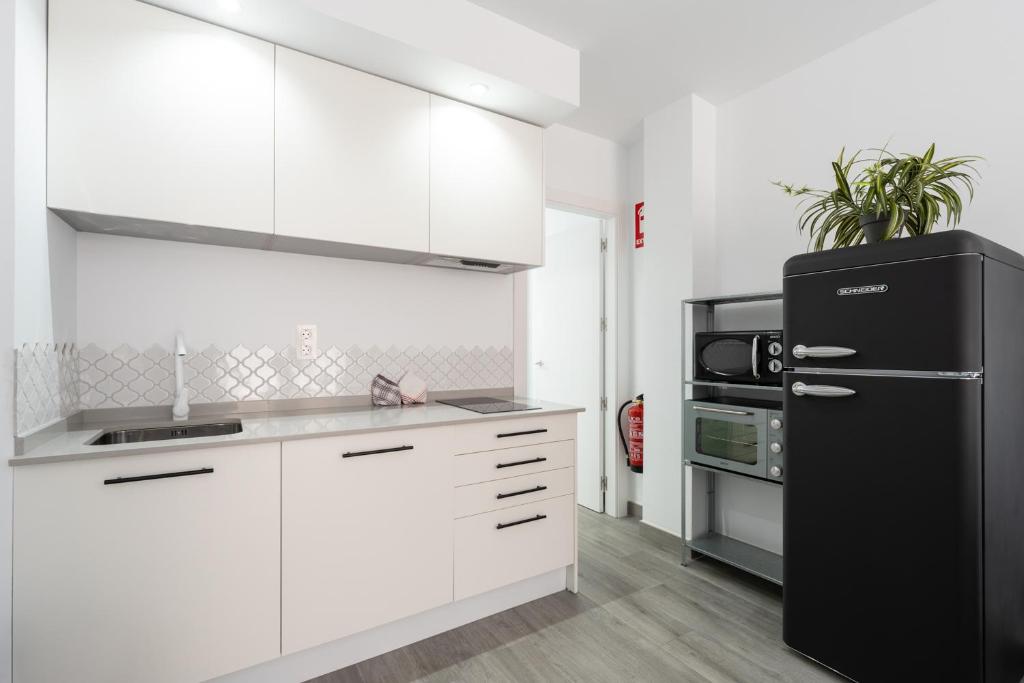 kuchnia z białymi szafkami i czarną lodówką w obiekcie Apartamentos Joya del Mar w mieście Torre del Mar