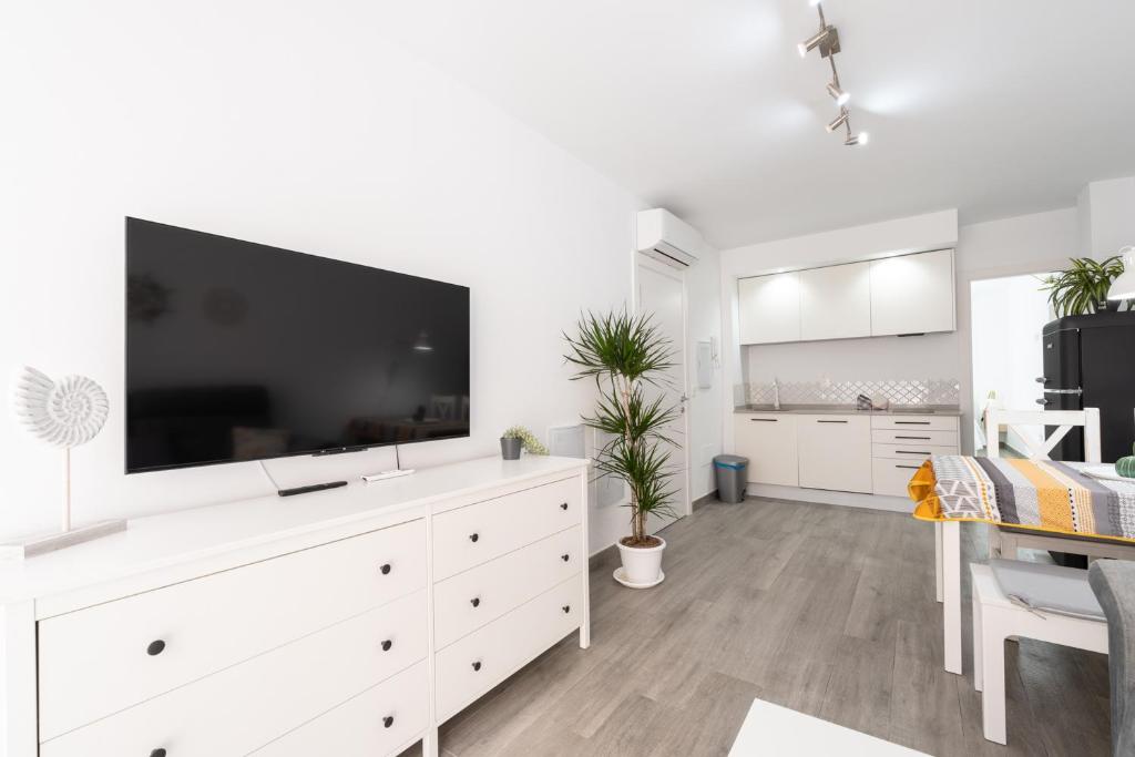 biały salon z dużym telewizorem na białej komodzie w obiekcie Apartamentos Joya del Mar w mieście Torre del Mar