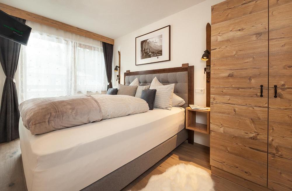 um quarto com uma grande cama branca e uma janela em Alpineas em Leutasch