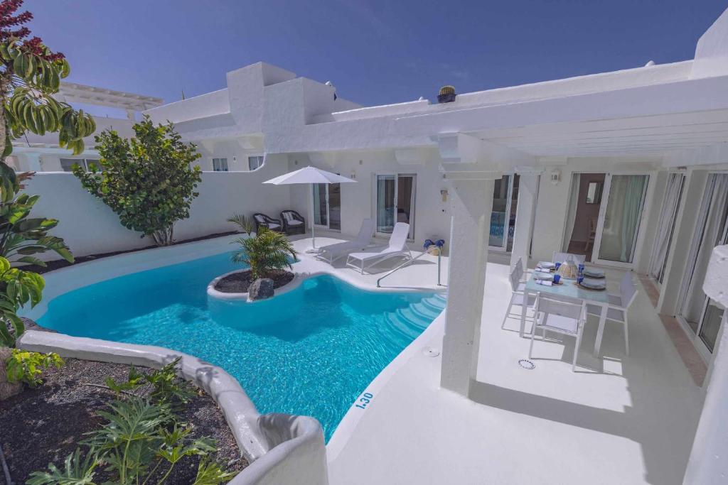 a swimming pool in the backyard of a house at Villa Tiguaro Piscina Climat Jacuzzy AC Villa 9 12 in Corralejo