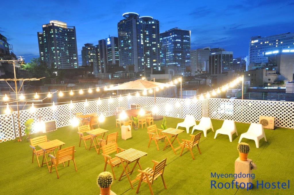 een dakterras met tafels en stoelen en een skyline van de stad bij OYO Rooftop Hostel in Seoul