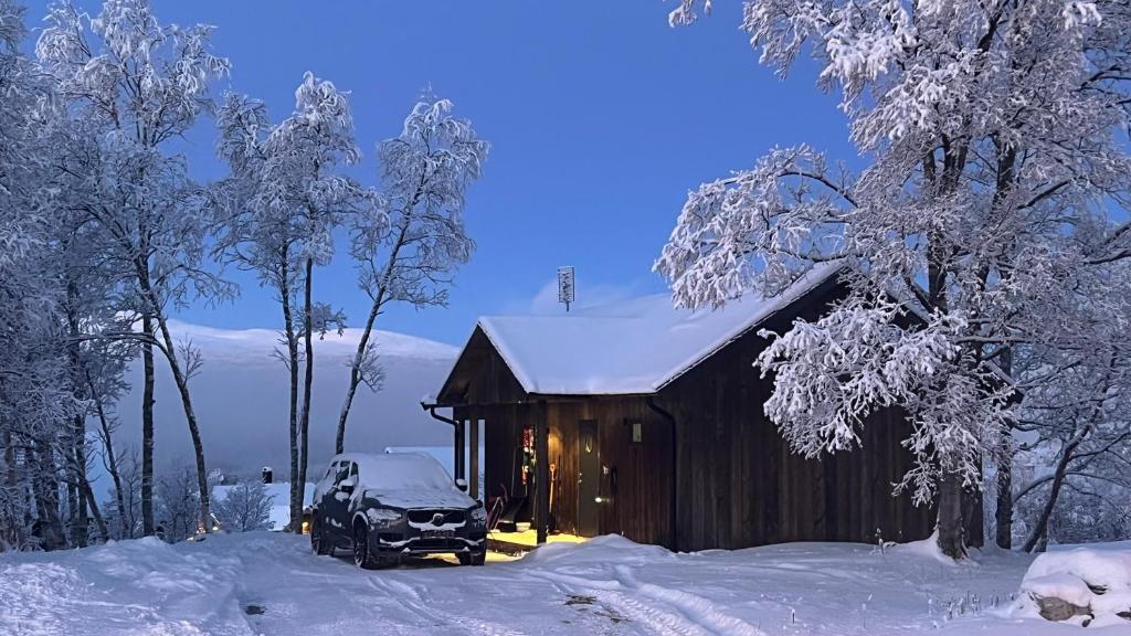 a snow covered cabin with a car parked next to it at Bruksvallarna - Modern fjällstuga med panoramautsikt och WiFi in Bruksvallarna