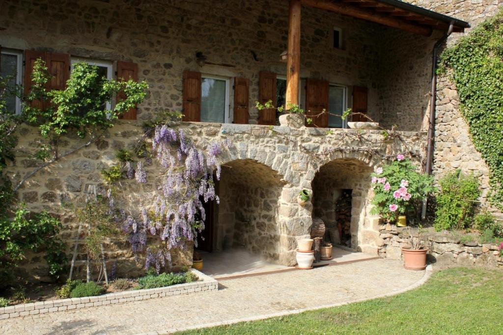 a stone house with purple flowers on the side of it at Le clos du martouret in Roisey