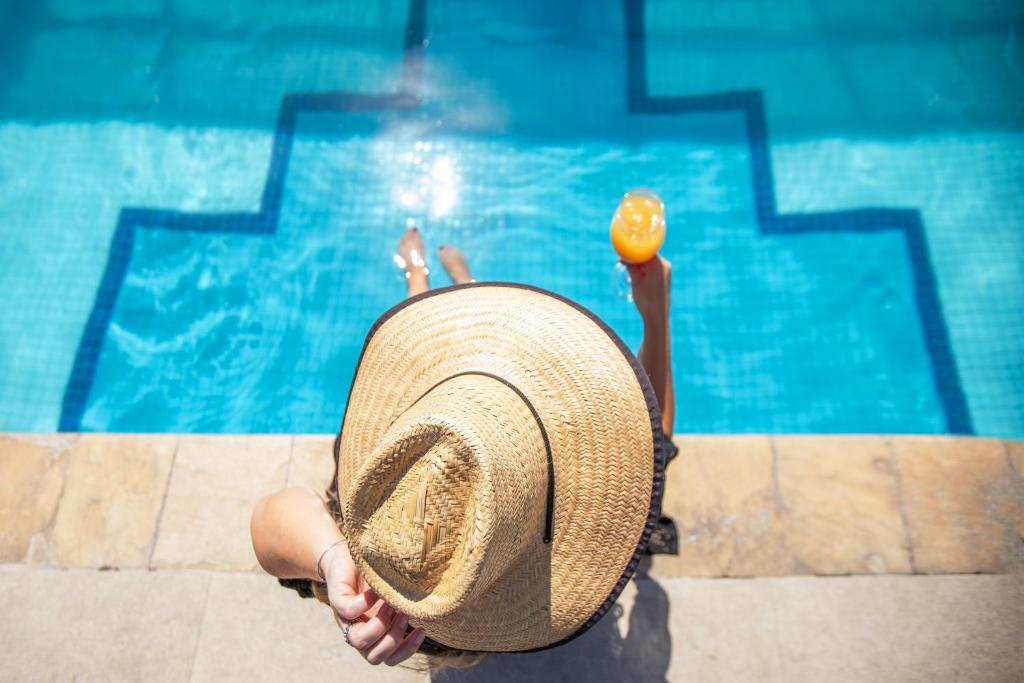 a person holding a straw hat in front of a swimming pool at São Paulo Tatuape, Affiliated by Meliá in São Paulo