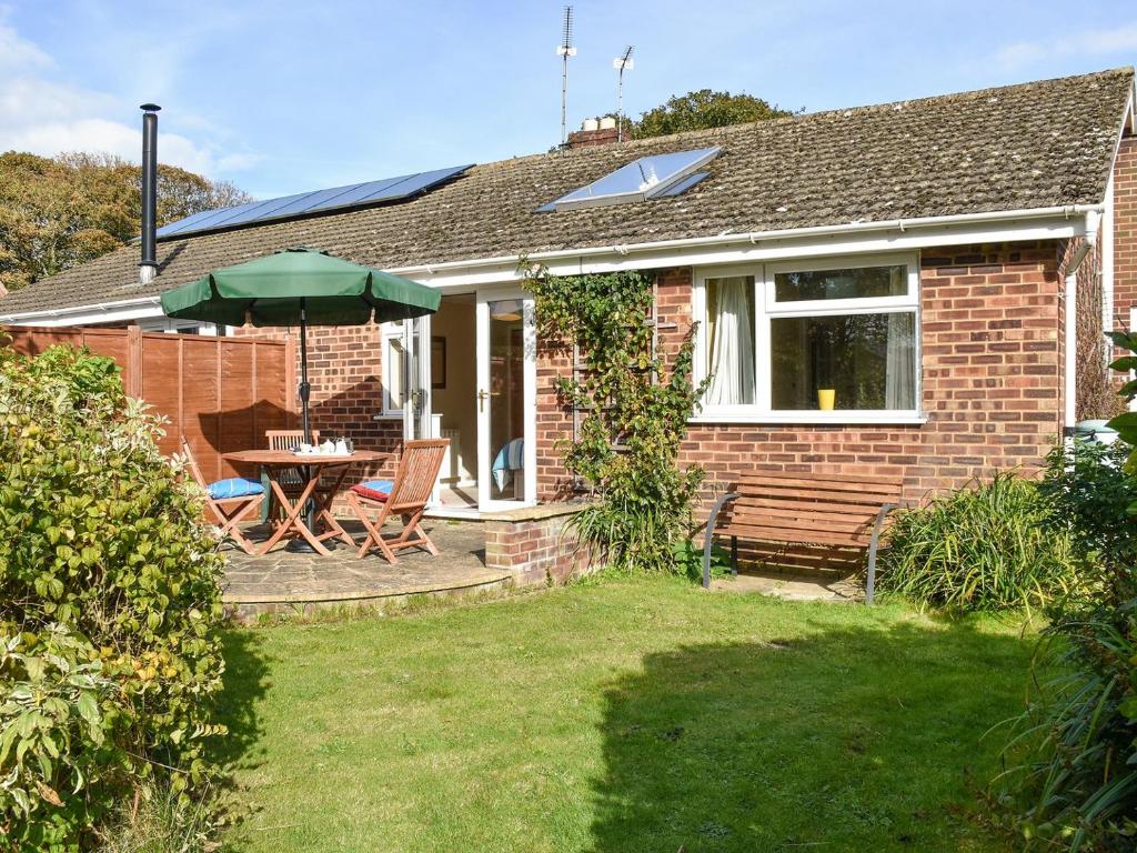 a brick house with a table and a green umbrella at Montana Cottage in Happisburgh