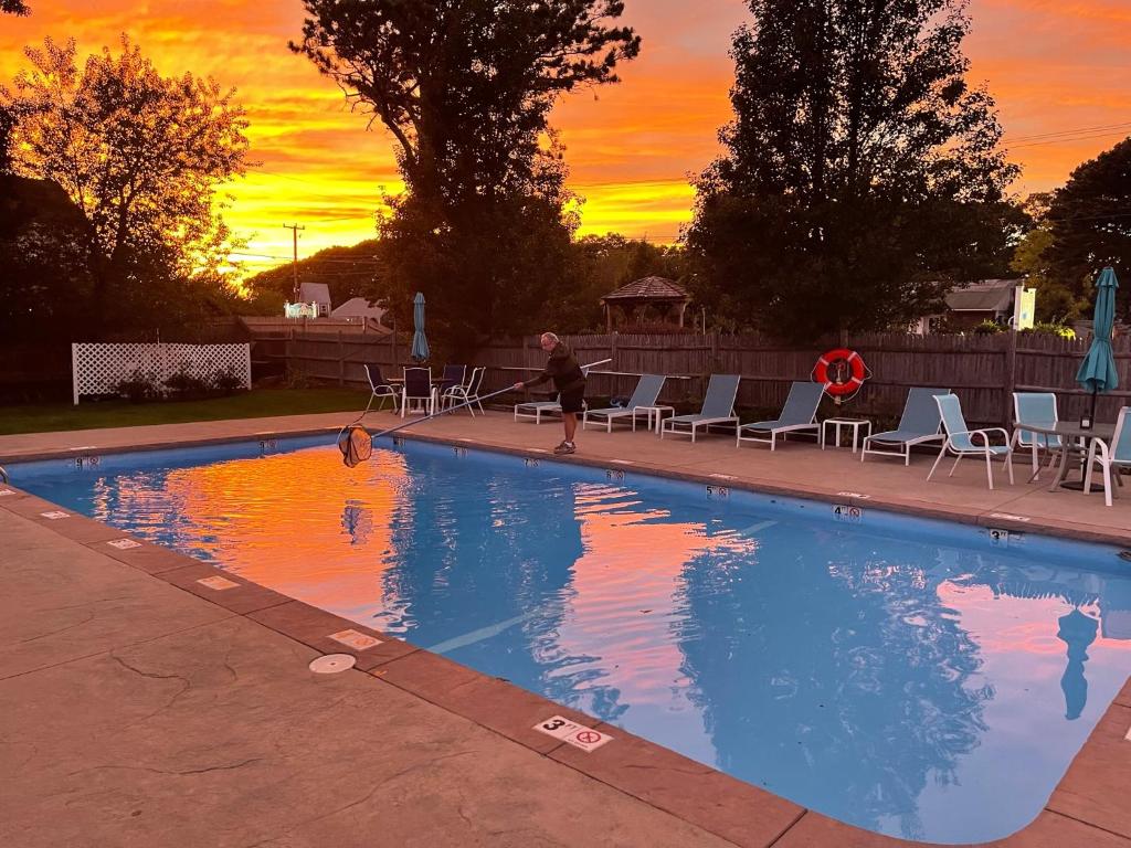 a person standing next to a swimming pool at sunset at The Escape Inn in South Yarmouth