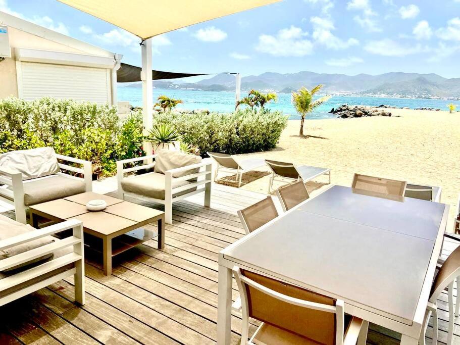 a wooden deck with a table and chairs on the beach at Villa Paradis Bleu Maison sur la plage, 2 chambres, piscines, tennis in Baie Nettle