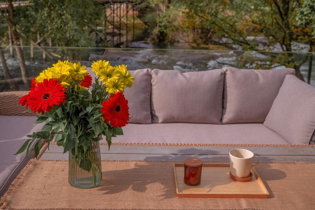 a vase of flowers on a table next to a couch at Waterfall Glamping Cabin in Bihać