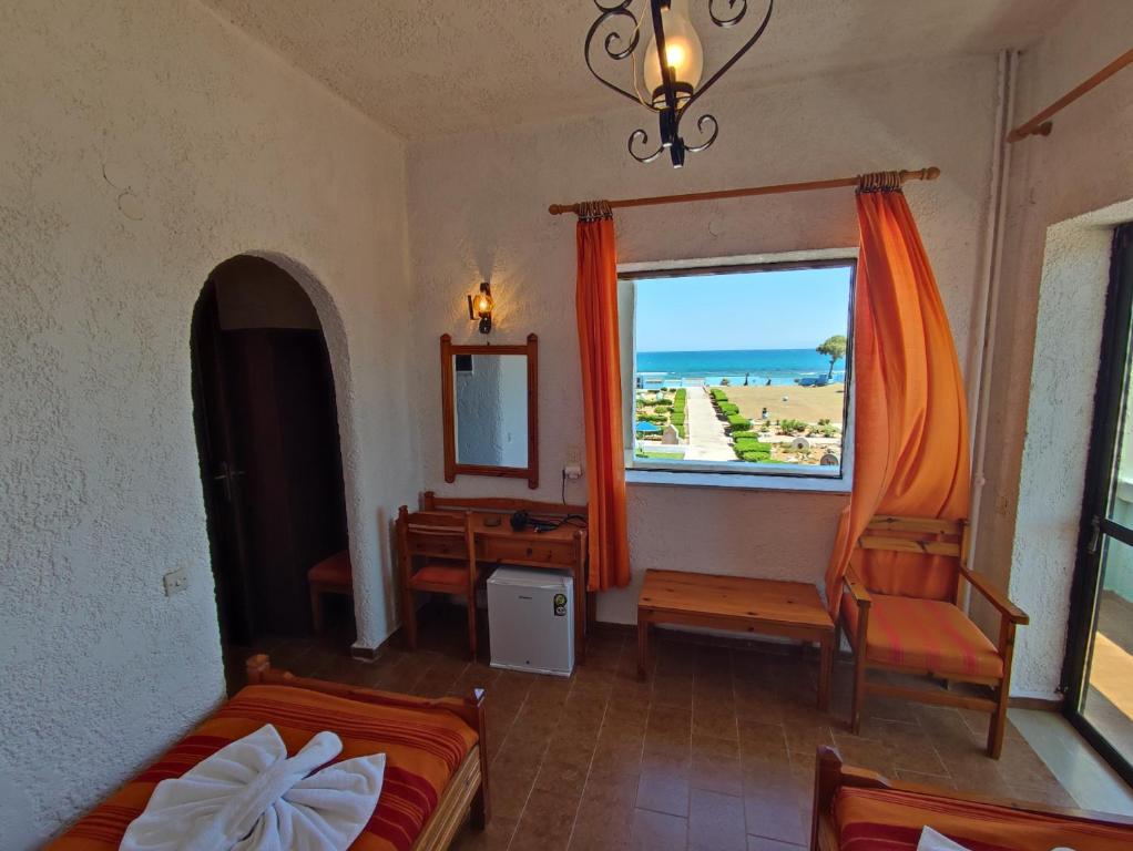 a bedroom with a bed and a window with a view of the ocean at Hotel Tsagarakis Beach in Amoudara Herakliou