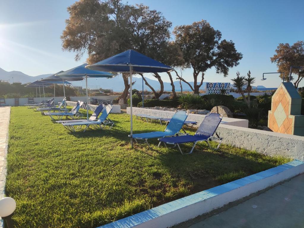 a row of lounge chairs and umbrellas on the grass at Hotel Tsagarakis Beach in Amoudara Herakliou