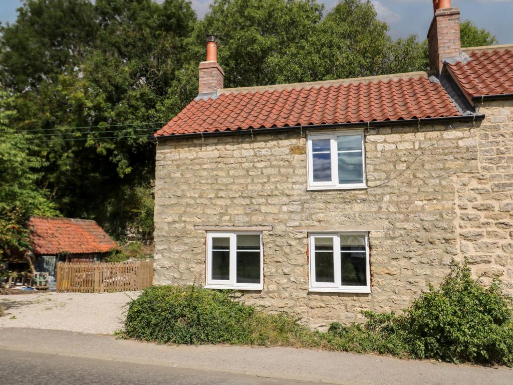 une maison en pierre avec des fenêtres blanches et un toit rouge dans l'établissement Yon Cottage, à York