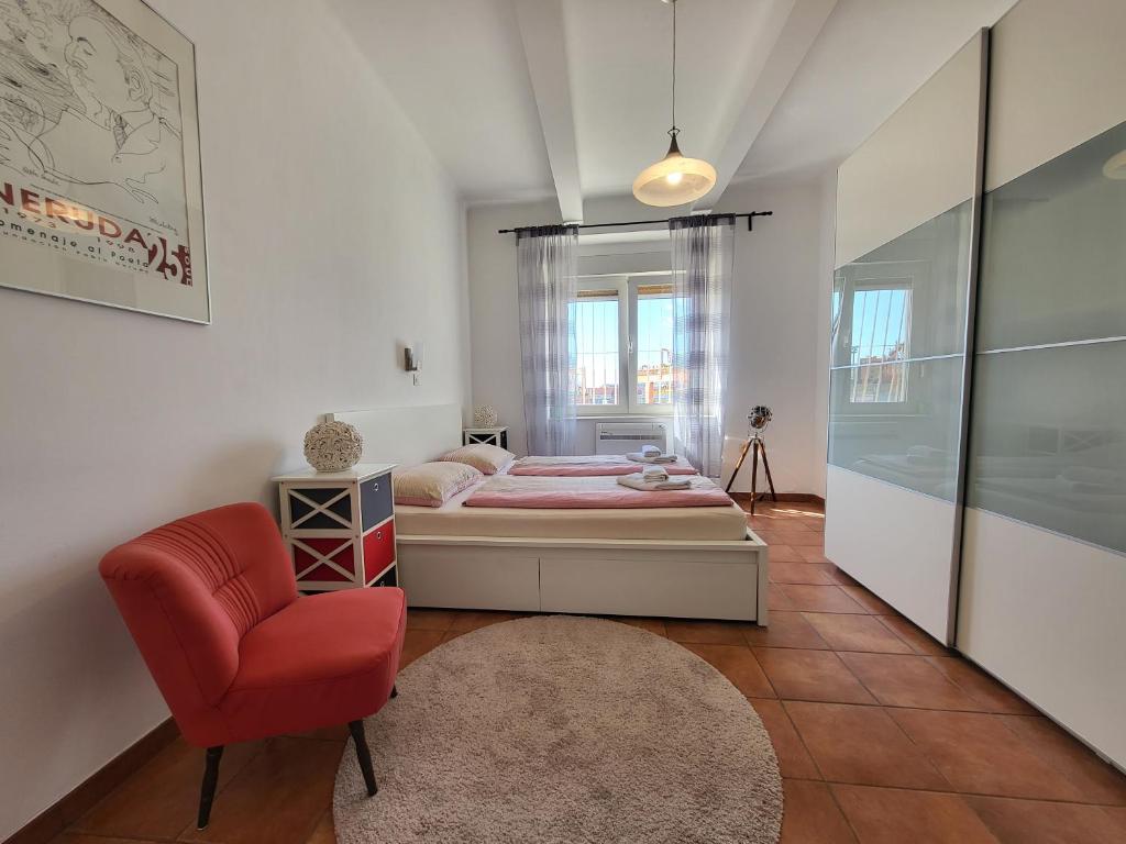 a bedroom with a bed and a red chair at Apartment Sablicevo - Near the Beach in Rijeka