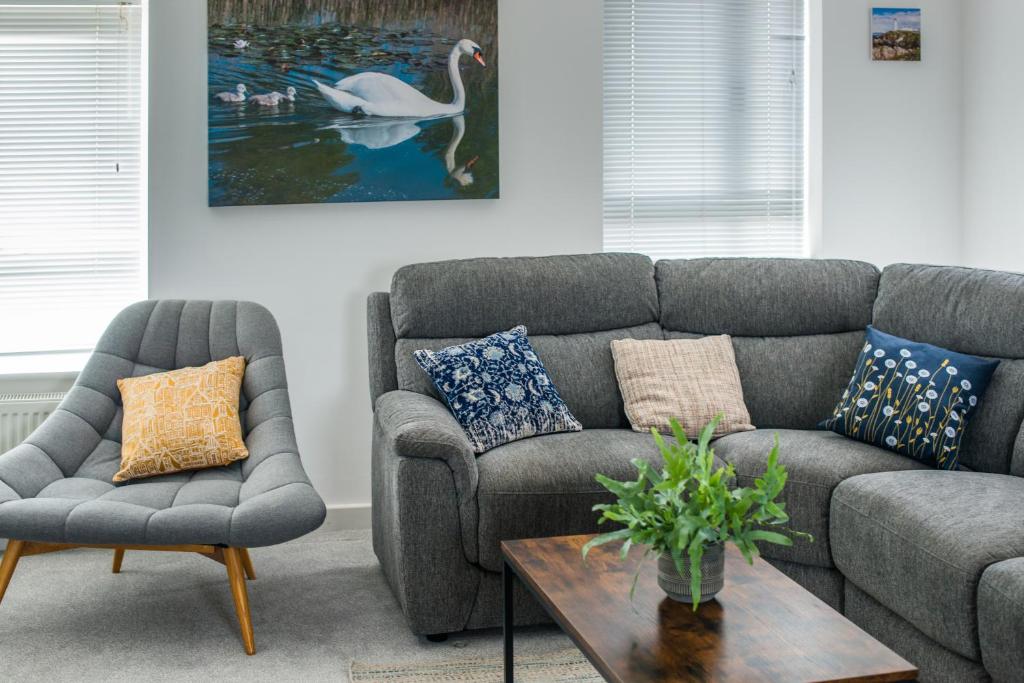 a living room with a couch and chairs and a swan painting at Cambridge Orchard Apartments - 2 double bedrooms in Cambridge