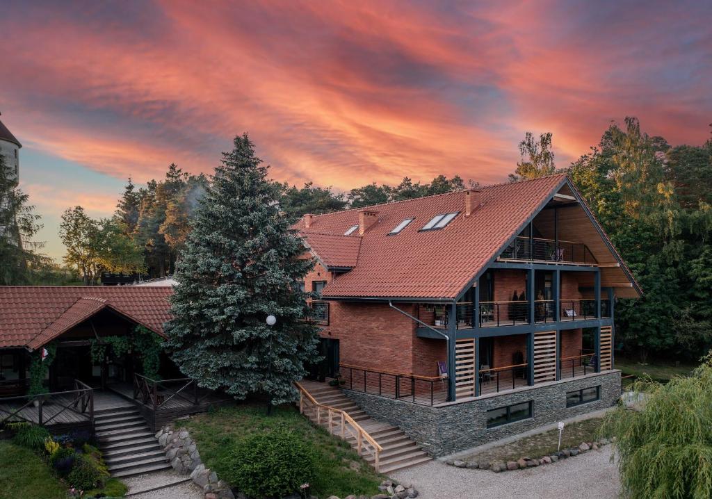 una casa con techo rojo y un árbol en Róża Wiatrów, en Węgorzewo