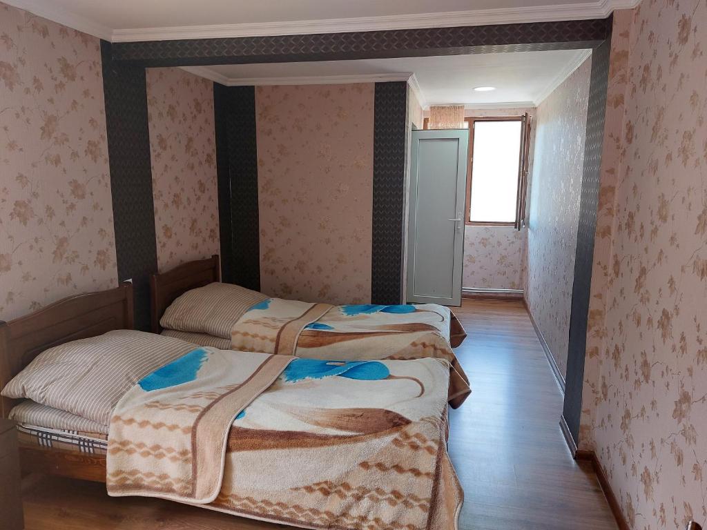 two beds in a room with pink wallpaper at Hotel Tekla in Ushguli