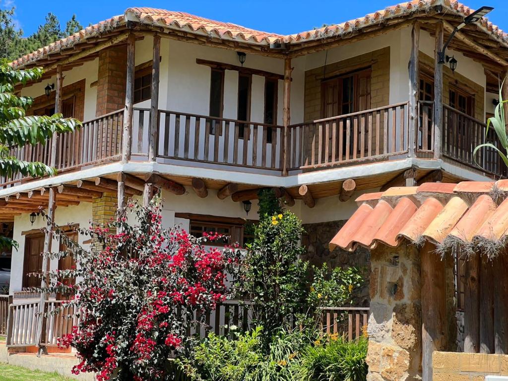 een huis met een balkon en bloemen ervoor bij Hermoso lugar familiar cerca a Villa de Leyva in Sutamarchán