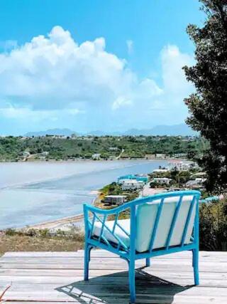 um banco azul sentado num convés a olhar para o oceano em Villa Kaiae em Sandy Ground Village