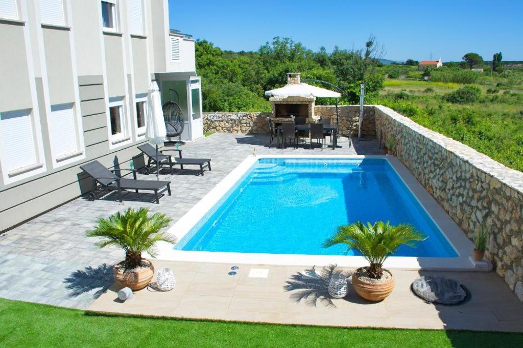 una piscina con dos palmeras junto a una casa en Luxury oaza Novalja, en Stara Novalja