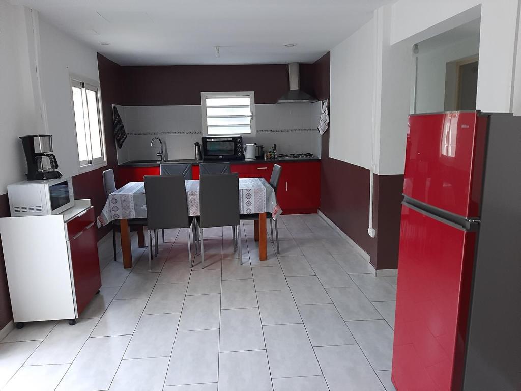 una cucina con tavolo, sedie e frigorifero rosso di Pomme de Pin a Cilaos