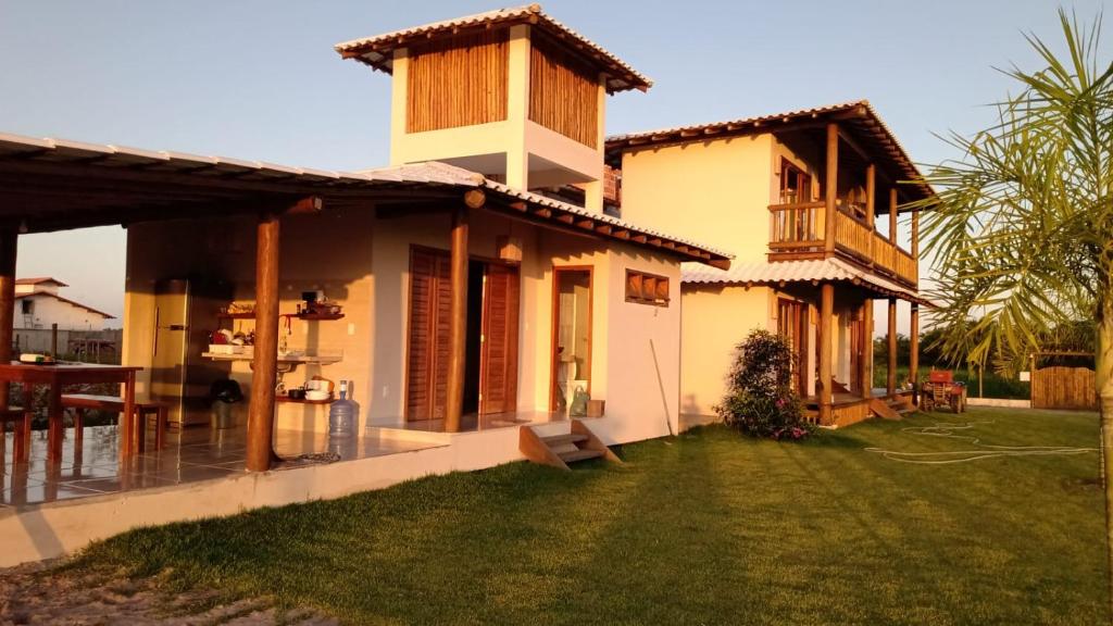 uma casa com um jardim de relva em frente em Casa D´Alicia em Maraú