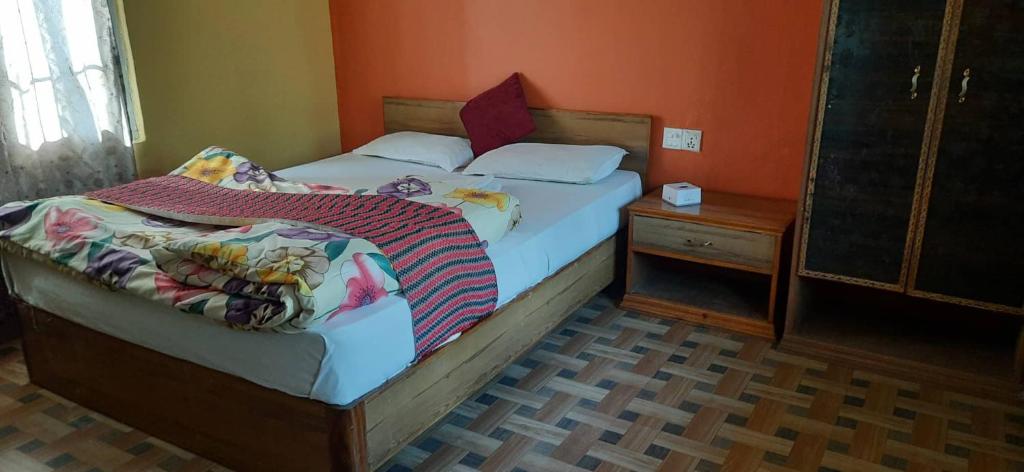 um quarto com 2 camas individuais e uma mesa de cabeceira em Gharbas Homestay - Sauraha em Sauraha