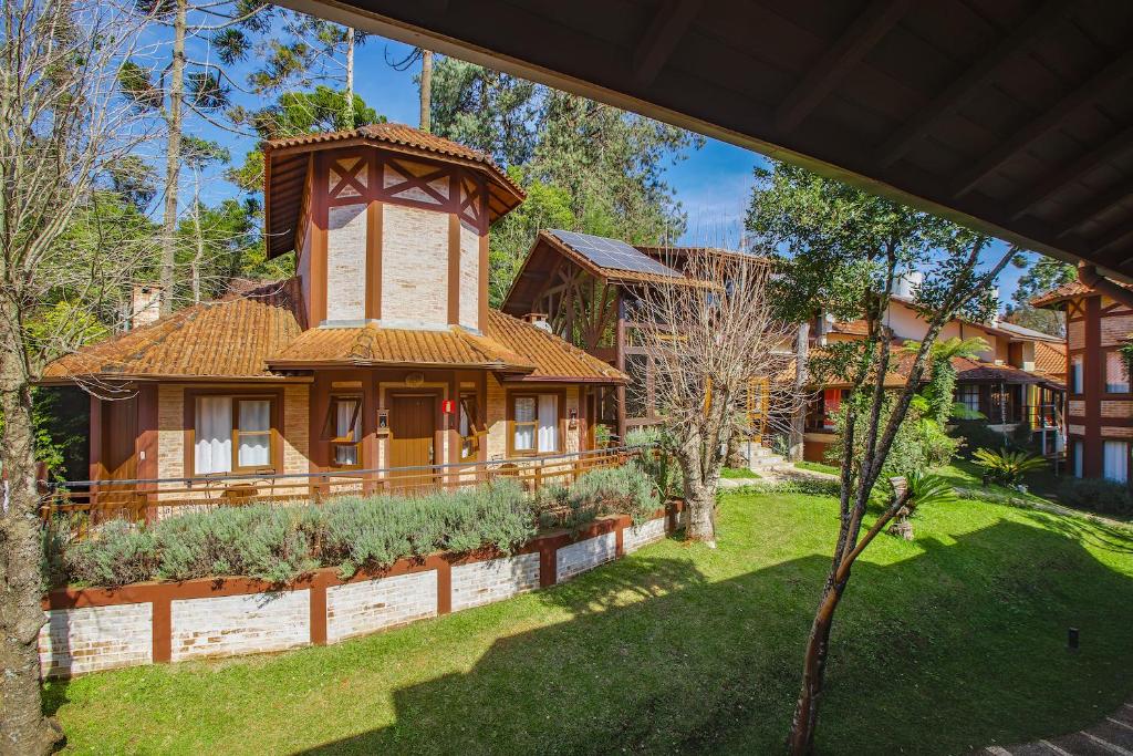 a house with a tower in the middle of a yard at Pousada Boutique Vilage de Minas in Monte Verde