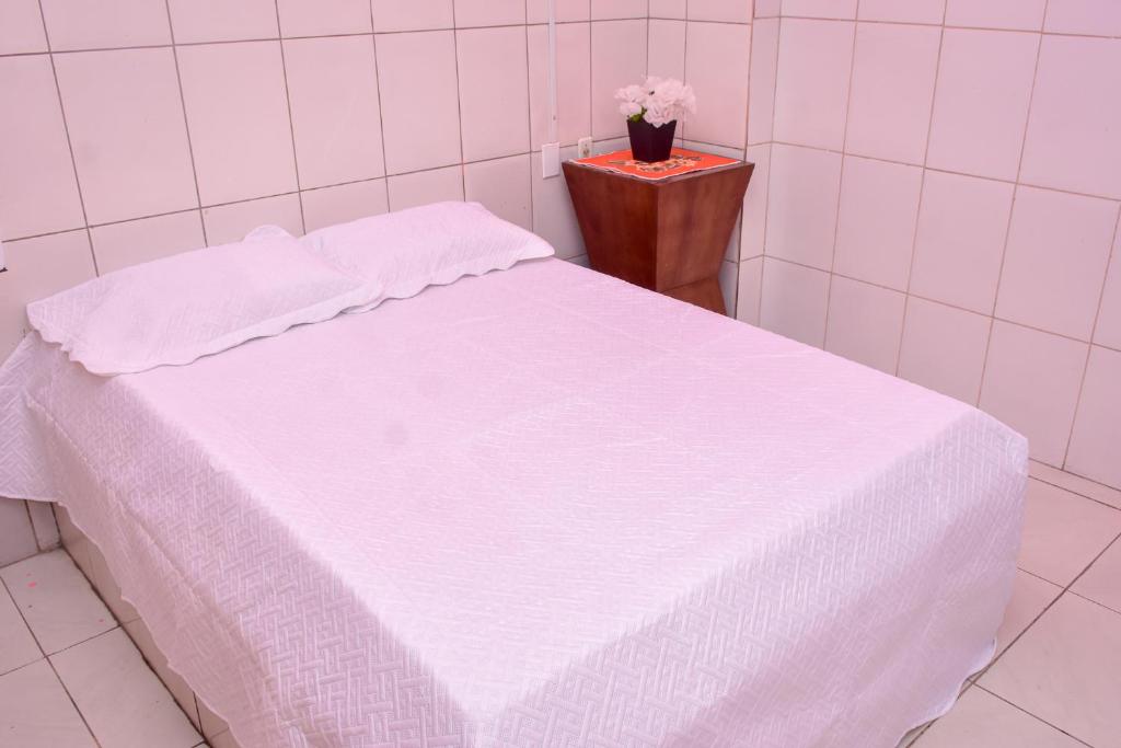 a white bed in a white room with a table at Pousada Aconchego in São Luís