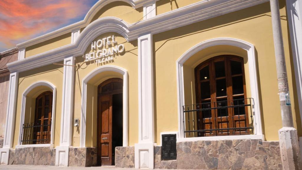 a building with three windows and a sign on it at Hotel Belgrano in Tilcara