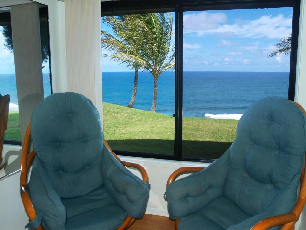 dos sillas frente a una ventana con el océano en Princeville Sealodge Unit D-4 en Princeville