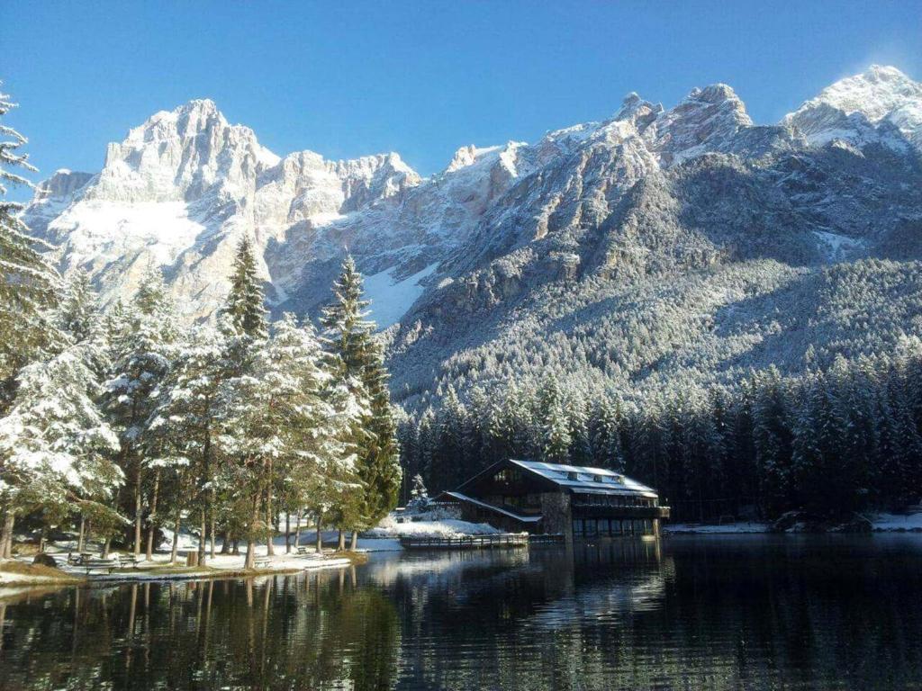 a cabin on a lake in front of a mountain at Chalet Al Lago in San Vito di Cadore