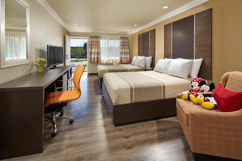 ein Hotelzimmer mit 2 Betten, einem Schreibtisch und einem Computer in der Unterkunft Eden Roc Inn & Suites near the Maingate in Anaheim