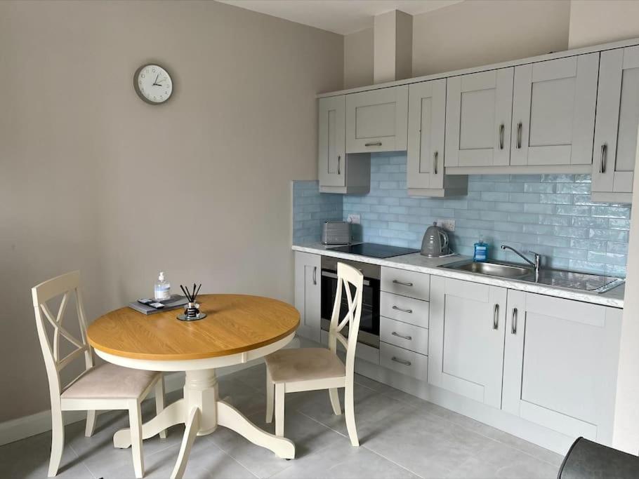 una pequeña cocina con mesa de madera y sillas en Erne Getaway No.7 Brand new 1 bed apartment, en Enniskillen