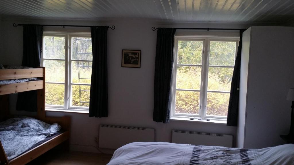 a bedroom with two windows and a bed in it at Stuga Gruvriset in Fredriksberg