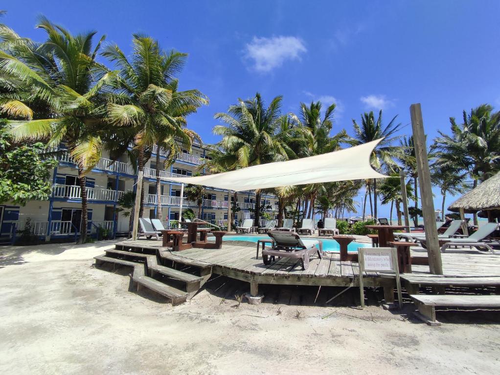 Un complejo con piscina, mesa y sillas. en Caribbean Villas Hotel, en San Pedro