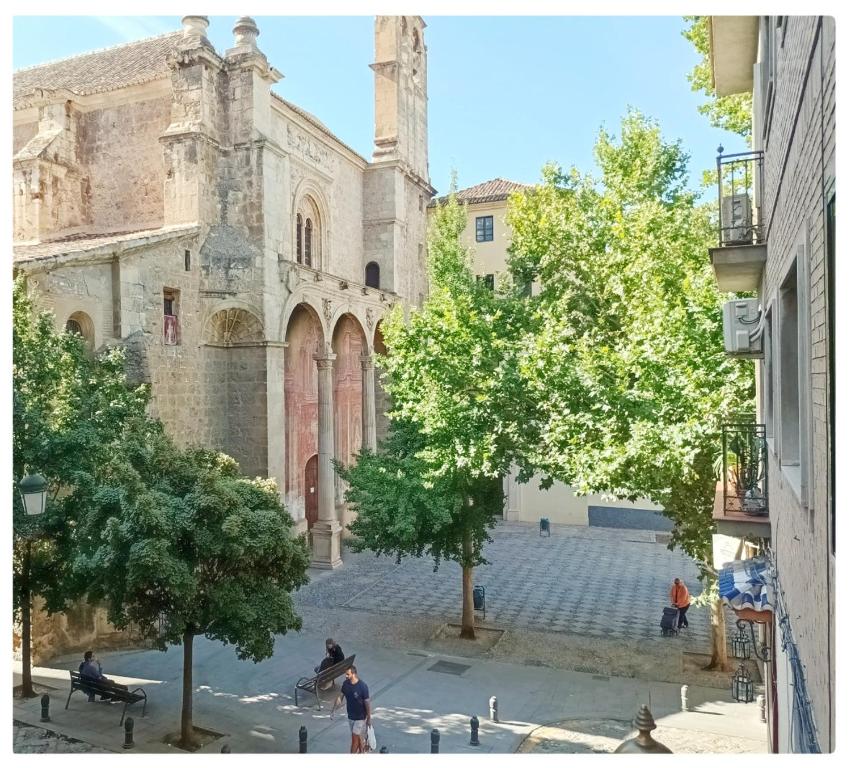 a view of a church with people sitting on benches in front of it at Santo Domingo Suites in Granada