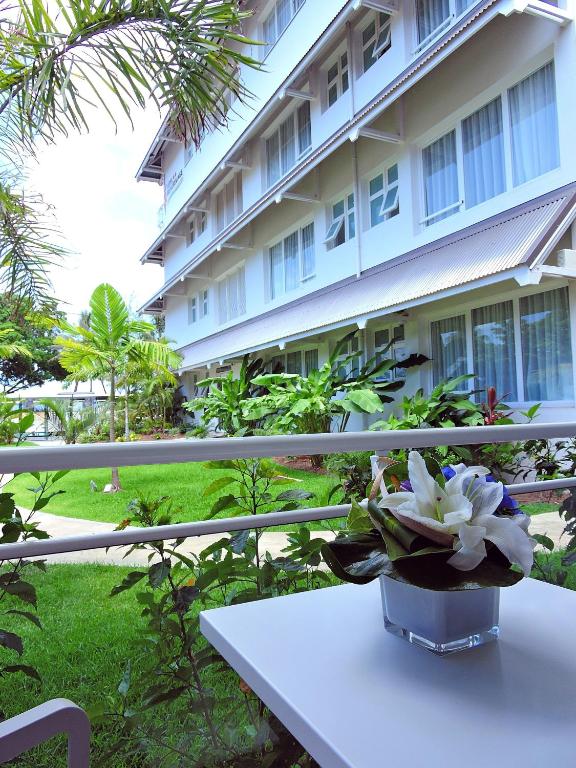 a vase of flowers sitting on a table in front of a building at Hotel Beaurivage in Noumea