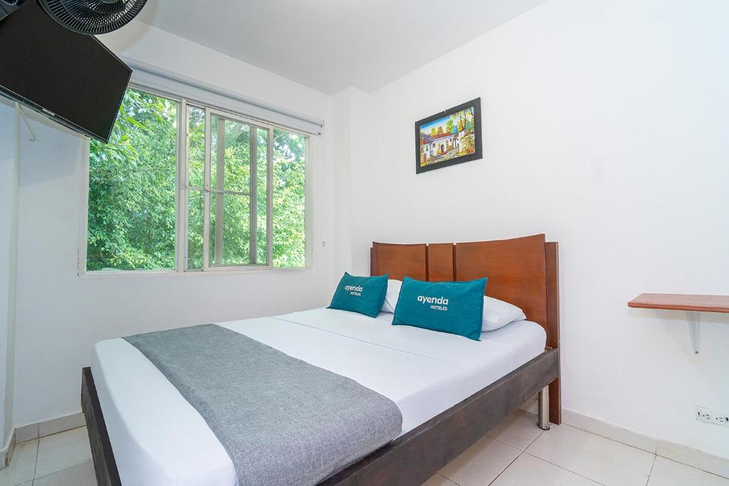 Un dormitorio con una cama con almohadas azules y una ventana en HOTEL HOSPEDAJE CANEY "Descanso & Tradición" Ayenda 1422, en Cali