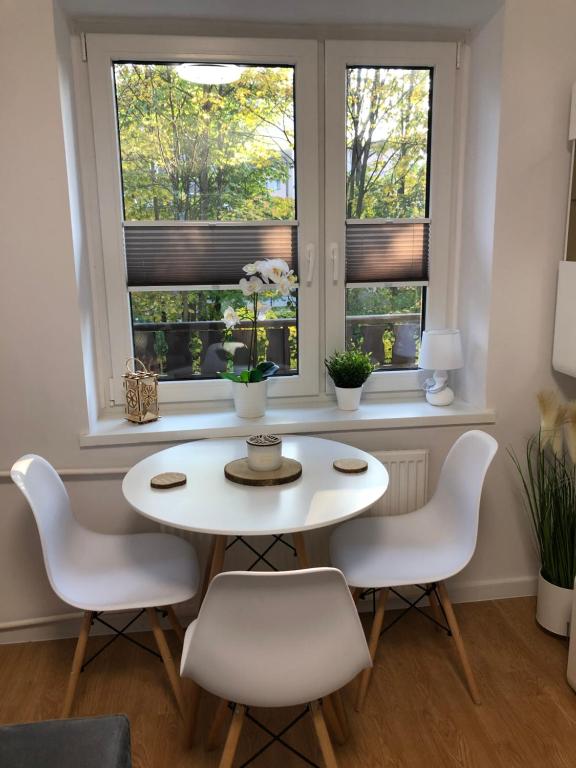 Apartament 4 osobowy في زاكوباني: طاولة بيضاء وكراسي في غرفة بها نوافذ
