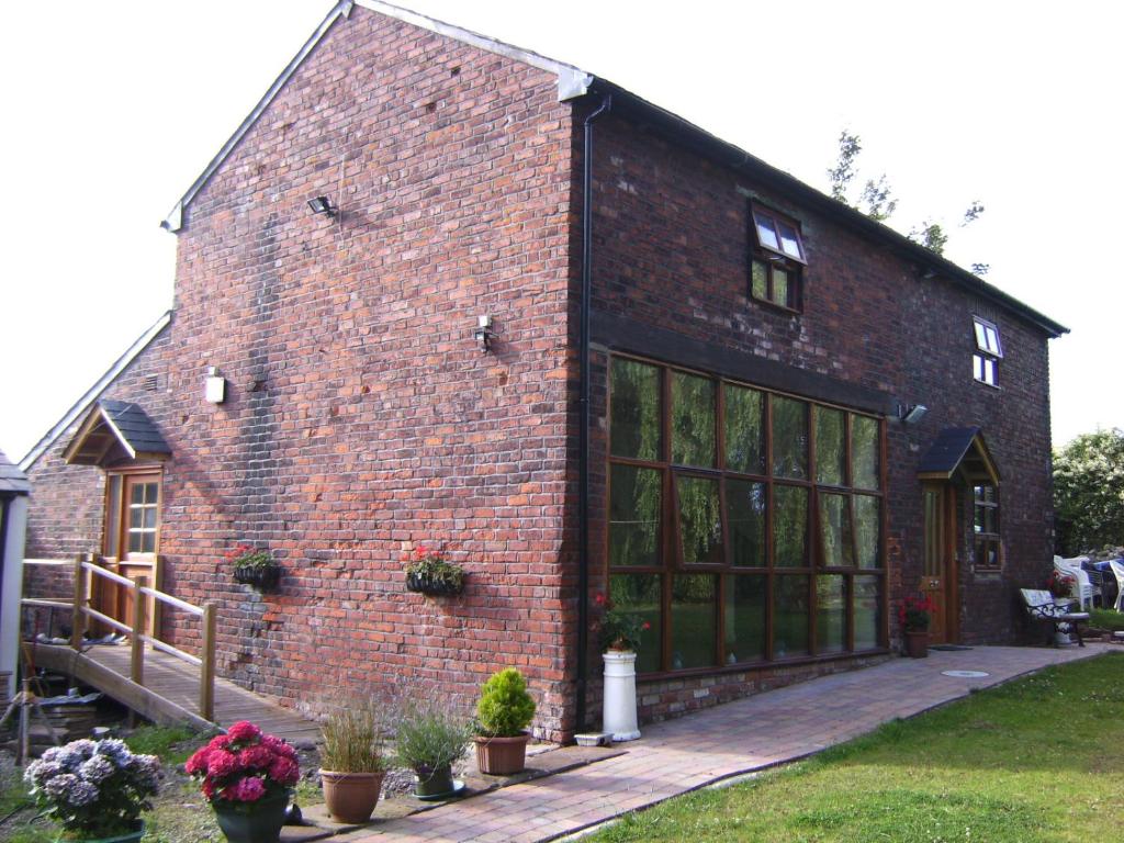 a brick building with large windows and potted plants at Brook Barn B&B in Hale