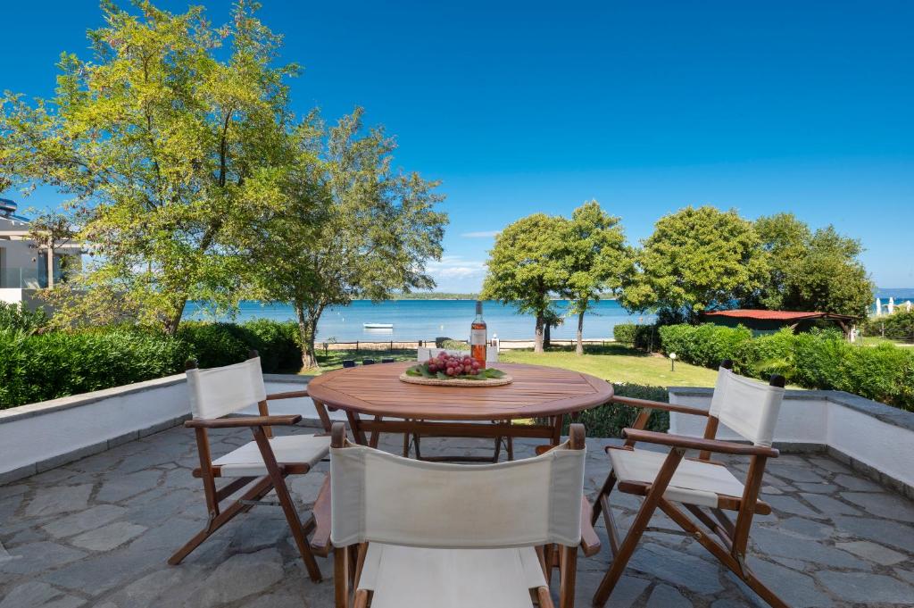 a patio with a table and chairs and the ocean at Seaside Vourvourou Villa in Vourvourou