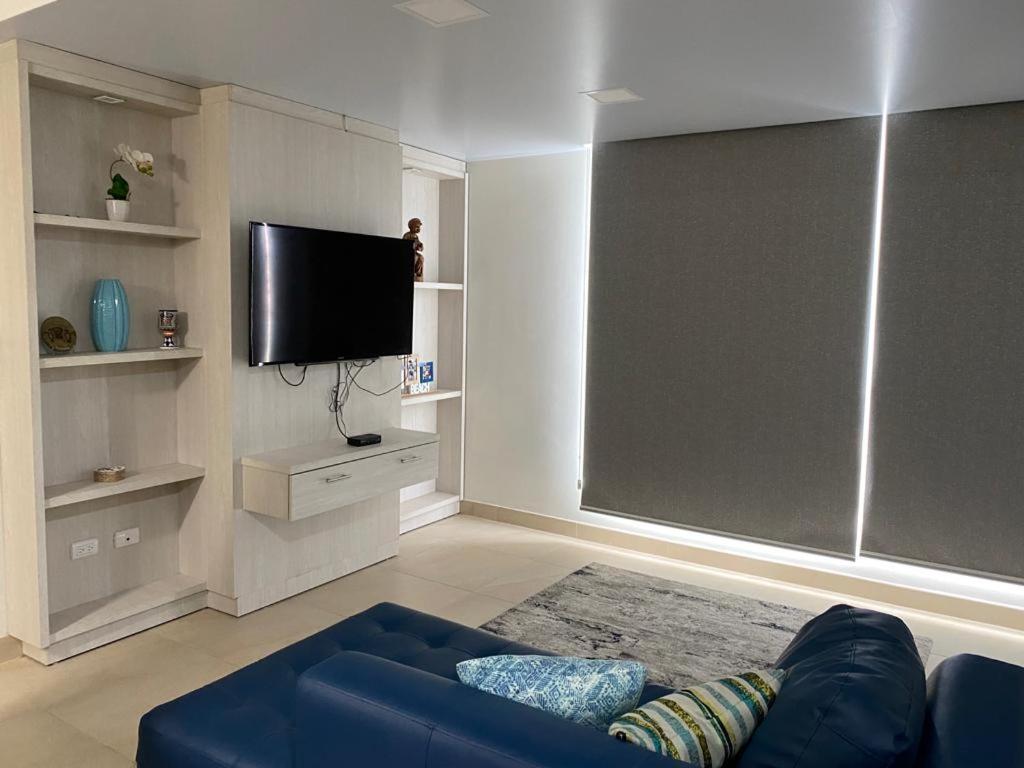 a living room with a blue couch and a flat screen tv at Alquilo hermoso departamento en Salinas, Ecuador in Salinas