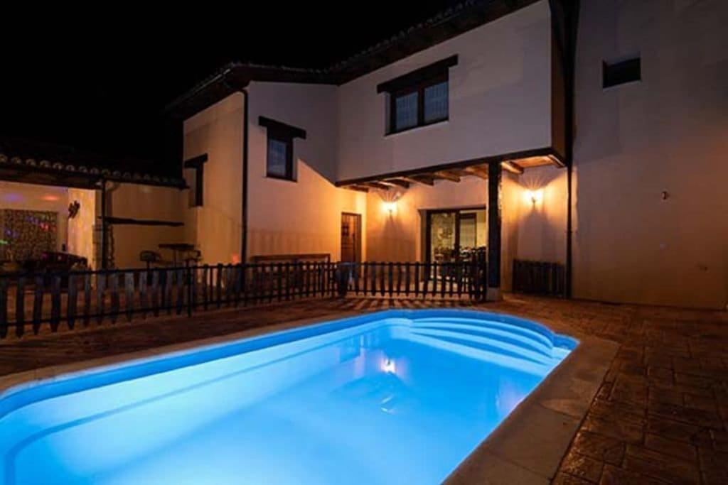 a swimming pool in front of a house at night at House of the Ribera - Quintana del Puente in Quintana del Puente