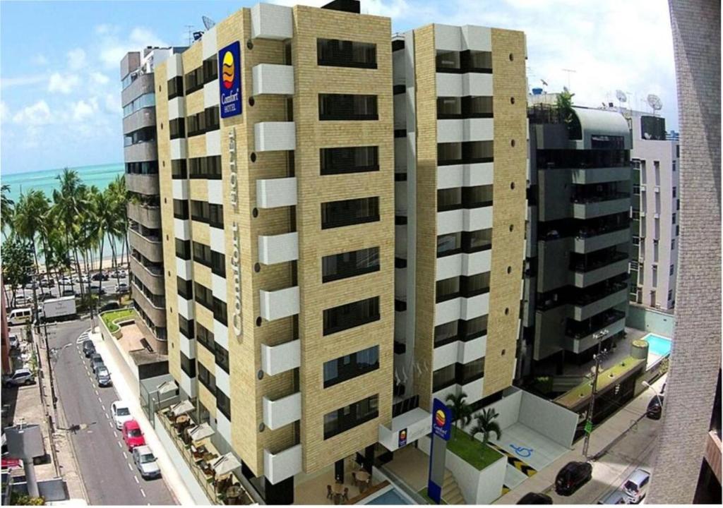 a tall building on a city street with the ocean at Comfort Hotel Maceió in Maceió