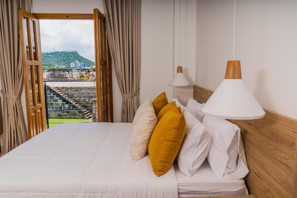 Un dormitorio con una cama con almohadas amarillas y una ventana en Del Mar Guest House en Cartagena de Indias