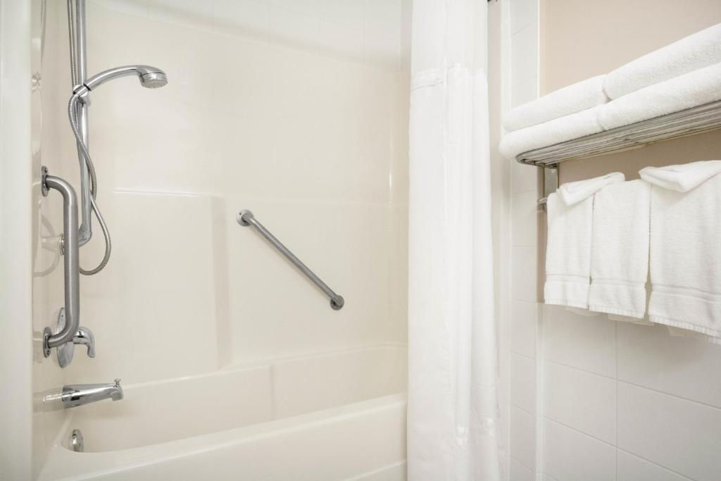 a bathroom with a shower and a bathtub with towels at Days Inn & Suites by Wyndham Langley in Langley