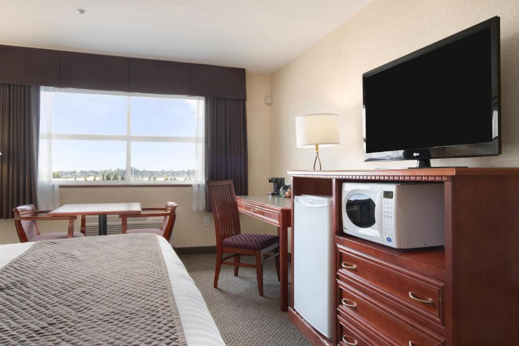 a hotel room with a bed and a desk with a microwave at Days Inn & Suites by Wyndham Langley in Langley