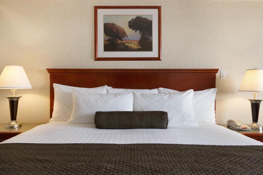 a bedroom with a bed with white pillows and two lamps at Days Inn & Suites by Wyndham Langley in Langley