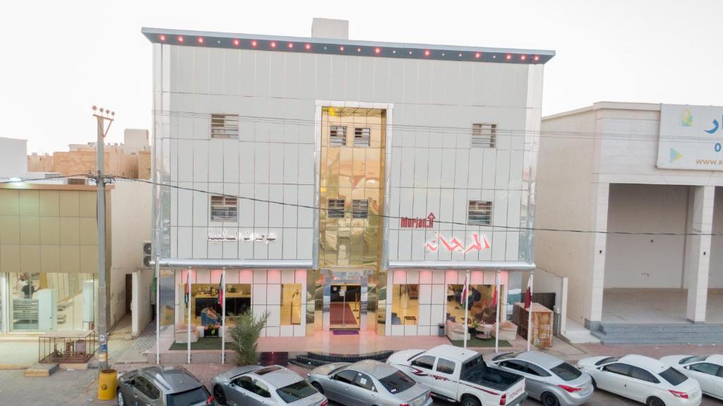 un edificio con coches estacionados en un estacionamiento en المرجانة للوحدات السكنية, en Rafha