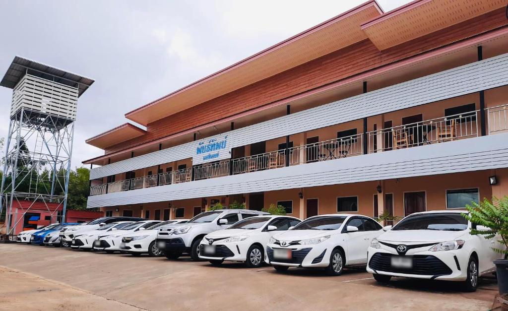 una fila de autos estacionados frente a un edificio en Pantip Residence en Nan