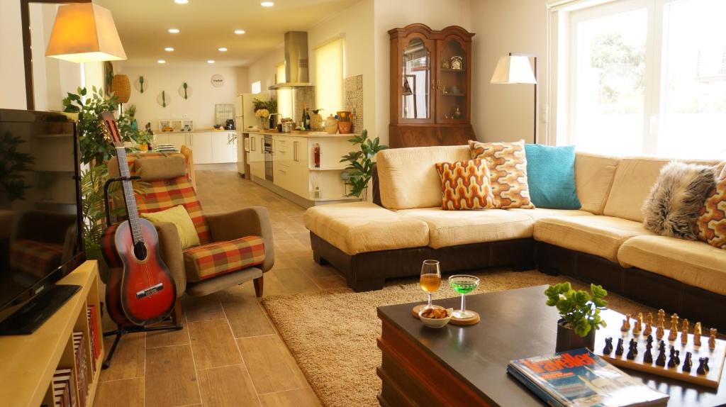 uma sala de estar com um sofá e uma guitarra em Casa do Areal em Mira
